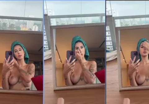 Mulher peituda do onlyfans se maquiando em frente ao espelho sem roupa